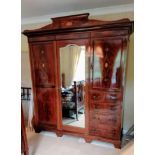 An Edwardian bedroom suite comprising: a treble wardrobe with carved pediment, interior fitted for