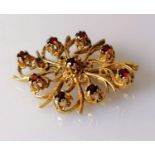 An oval 9ct yellow gold filigree brooch decorated with nine garnets, hallmarked, 30mm x 40mm, 9.18g