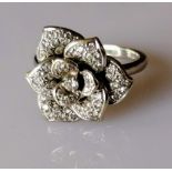 An 18ct white gold nine-petal diamond encrusted flower ring, the central diamond 0.05 carats