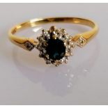 A 9ct yellow gold, diamond, and sapphire cluster ring, set with a mixed oval-cut sapphire, within