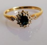 A 9ct yellow gold, diamond, and sapphire cluster ring, set with a mixed oval-cut sapphire, within