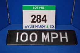A 100 MPH Number Plate utilising Silver Coloured Plastic Numbers and Letters Affixed to A Black