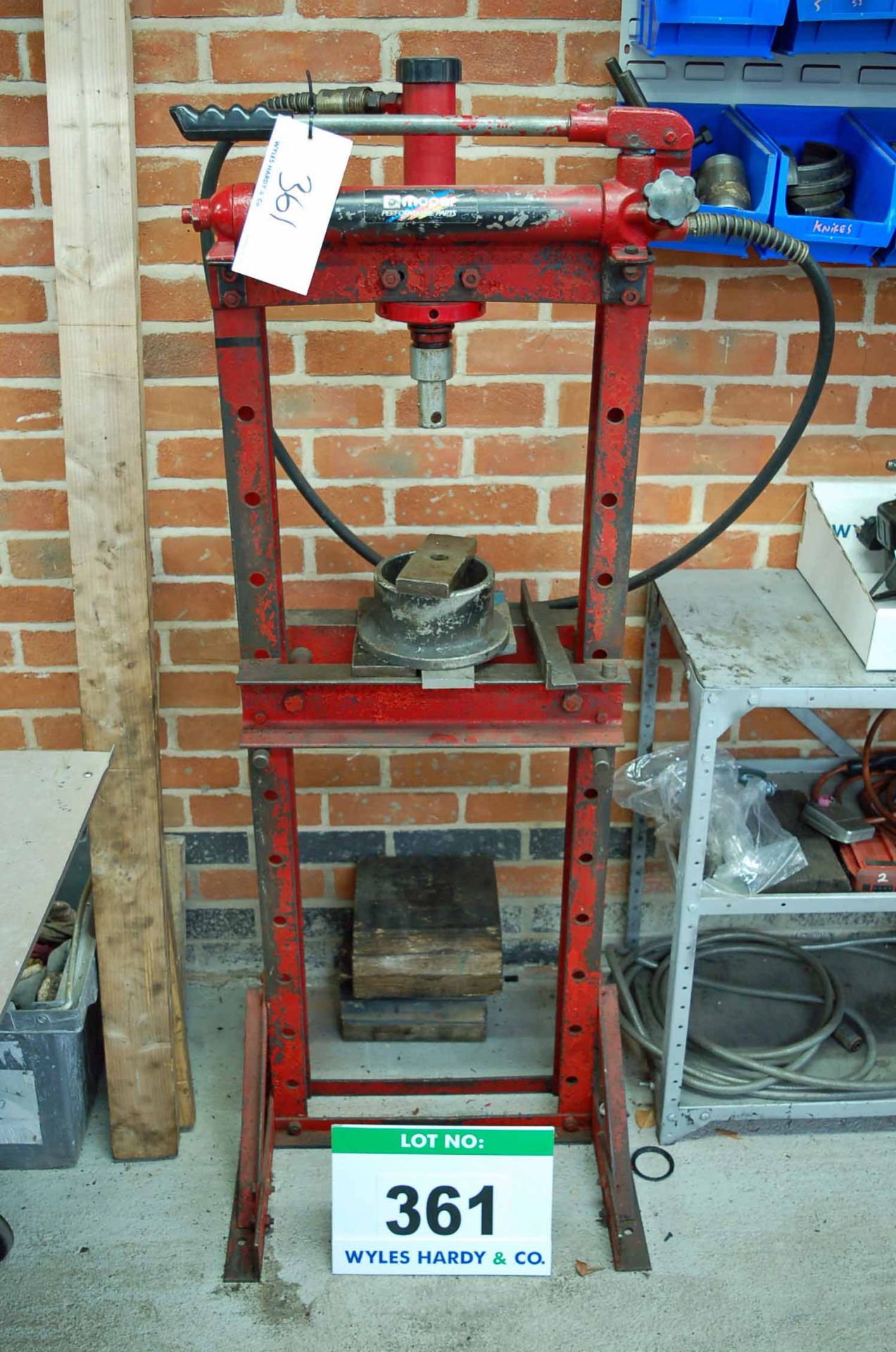 An Unbranded Manual Hydraulic Bearing Press with a Wall Mounted Lin Bin Rack Containing Accessories