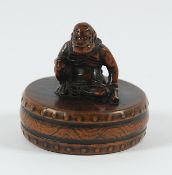 NETSUKE ONI AUF TROMMEL, Buchsbaum, fein geschnitzt und dunkel akzentuiert graviert, Zähne und Knopf