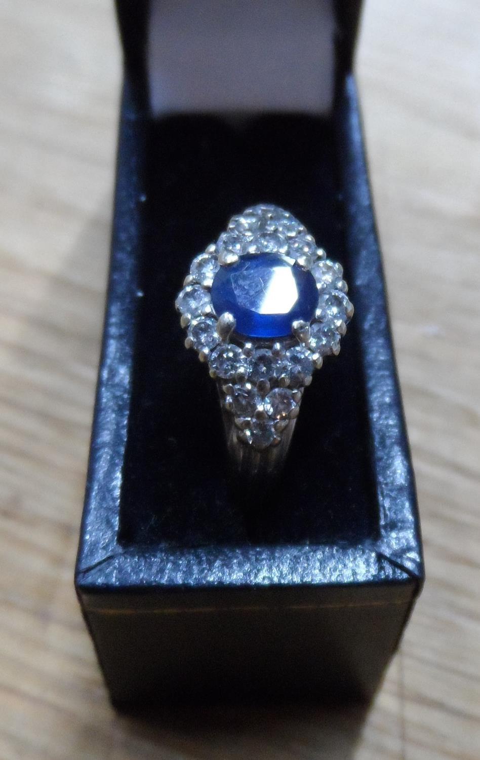 Fine quality, oval cut Sapphire surrounded by 18 round cut, high quality diamonds set in white