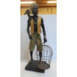 Pleasing resin figure of a Nubian man with a monkey on his shoulder carrying an empty metal bird