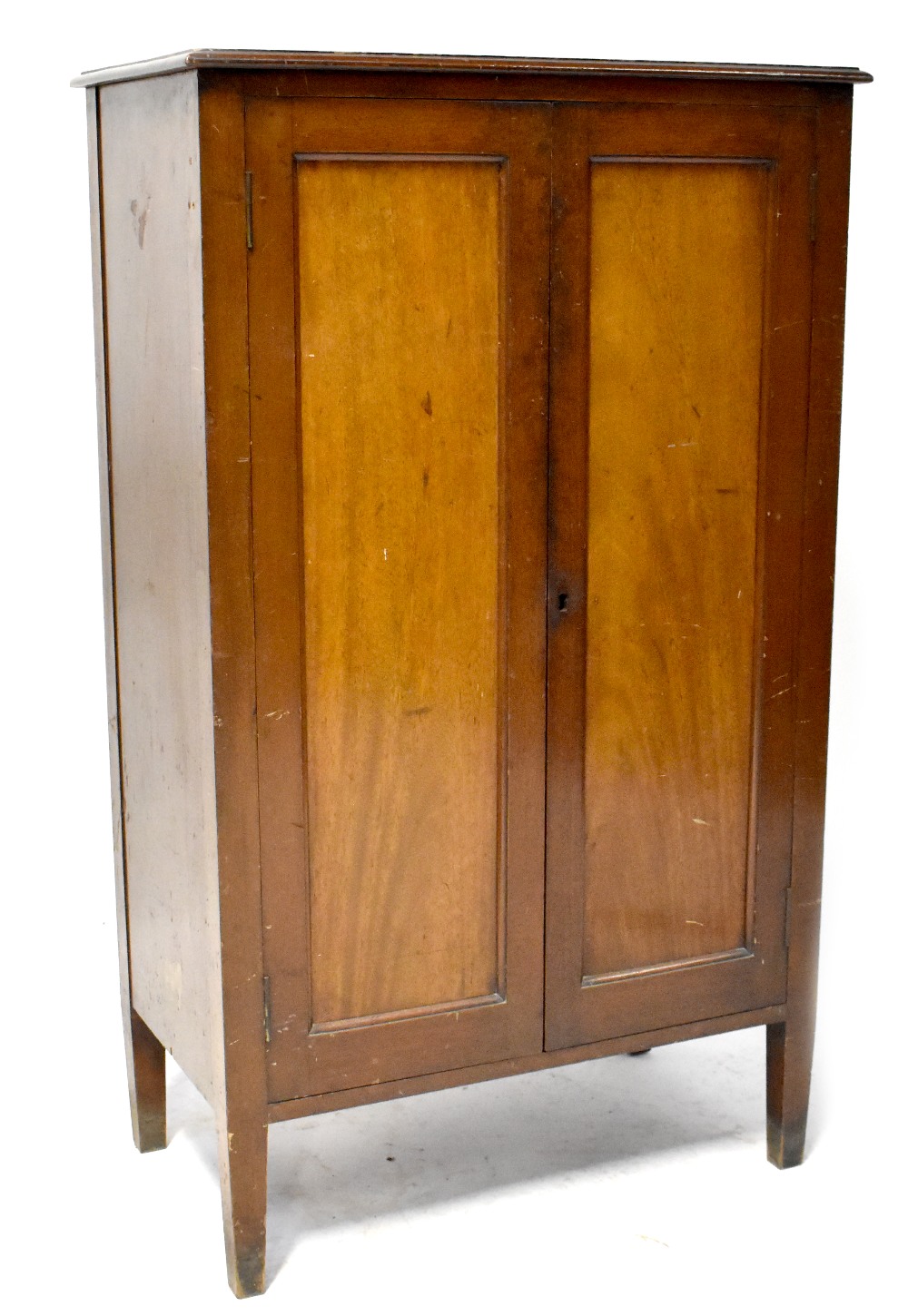 A mahogany floorstanding cupboard with pair of panelled doors enclosing shelves and on square