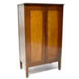 A mahogany floorstanding cupboard with pair of panelled doors enclosing shelves and on square