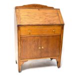 A mid-20th century oak bureau with fall front above one long drawer and cupboard doors,