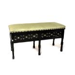 An Edwardian ebonised duet piano stool with pierced decorative frieze and overstuffed lift up