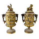 A pair of cast metal covered urns decorated with putti, the handles in the form of grapes and vines,