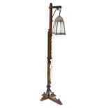 An early 20th century Arts & Crafts standard lamp with wrought iron decoration to the base and top