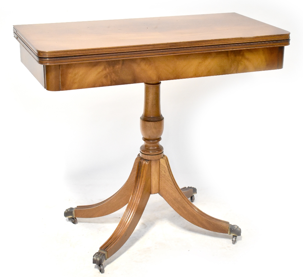 A 19th century style mahogany fold-over card table on a turned column with four outswept legs to