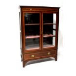 An Edwardian inlaid mahogany display cabinet comprising a pair of glazed cupboard doors above