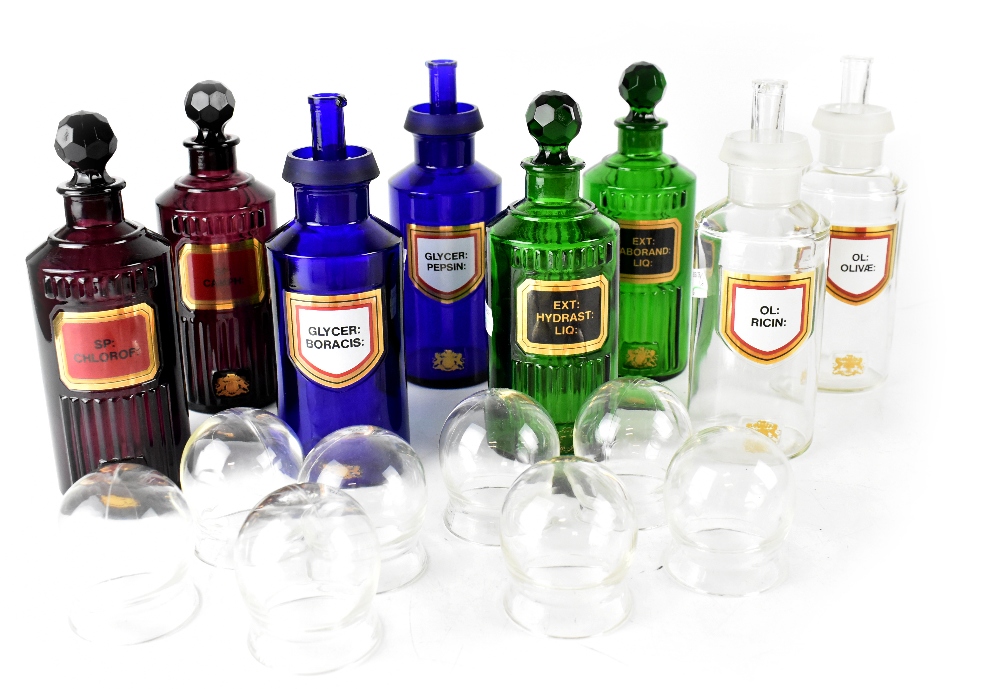 A group of eight apothecary-style glass bottles, two clear, two green ribbed,