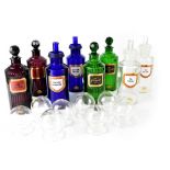 A group of eight apothecary-style glass bottles, two clear, two green ribbed,
