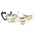 A Victorian hallmarked silver three-piece tea service with scroll repoussé decoration,