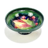 WALTER MOORCROFT; a footed pin dish decorated in the 'Leaf and Berry' pattern on a green/blue
