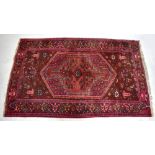 A large Bokhara-type rug with stylised detail on a predominantly red ground, 220 x 127cm.