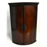 A Georgian mahogany bowfront corner cupboard with H-hinges, height 103cm, width 71cm, depth 50cm.