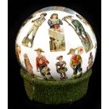 A Victorian decalcomania sphere, decorated with stylised figures and raised on later green textile