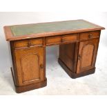 An early 20th century kneehole desk with green leather inset top above three drawers and two