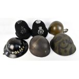 Four WWII and later military helmets, Brodie-type repainted with police decal, a police helmet (