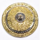 An unusual white metal and parcel gilt miniature Cellini shield with relief decoration, diameter 6.