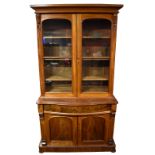 A Victorian serpentine fronted bookcase, the upper section with three adjustable shelves above