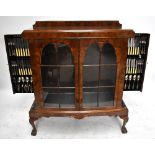 A 1930s/40s figured walnut display cabinet of slightly bowfront form with twin glazed doors and