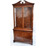 A reproduction mahogany bookcase with glazed upper section enclosing adjustable shelves, above a