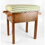 An early 20th century oak box seat piano/dressing stool with twin scrolling handles and square