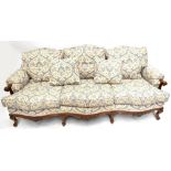 A reproduction French-style walnut settee of serpentine outline with loose cushions, carved detail