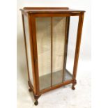 An early 20th century walnut display cabinet with single glazed door enclosing two fixed shelves,