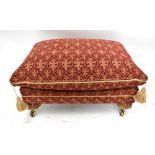 A modern upholstered footstool with loose cushion, rope detail and lobed legs to brass caps and