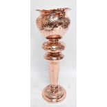 A late Victorian copper jardinière on stand with repoussé scrolling and floral detail, raised on a