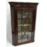 An early 19th century mahogany flat fronted corner cabinet, the single astragal glazed door