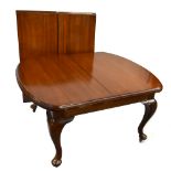 An Edwardian mahogany wind-out extending dining table with two extra leaves, raised on cabriole