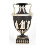 WEDGWOOD; a late 19th century black and white jasper dip urn with twin mask scrolling handles,