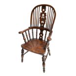 A reproduction elm seated spindle back Windsor armchair raised on turned column supports.