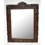 A late 19th century Arts & Crafts oak rectangular wall mirror elaborately carved with stylised