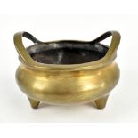 A Chinese polished bronze twin handled censer on three feet, with Xuande character mark to base,