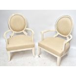 A modern pair of cream painted over-sized upholstered elbow chairs with oval backs and square