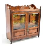 An early 20th century oak smoker's cabinet, the twin glazed doors enclosing four short drawers and