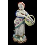 A large late 19th century Continental porcelain figure of a young girl holding a basket of fruit,