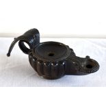 AFTER THE ANTIQUE; a bronze oil lamp with lobed circular body and stylised swept loop handle,