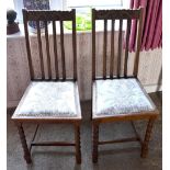 A pair of 1930s oak bedroom chairs with carved top rails and padded seats to barley twist and