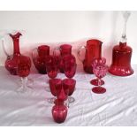 A small group of cranberry glass including a large bell, various wine glasses, jugs, also