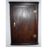 An early 19th century oak flat fronted hanging corner cupboard with shaped brass hinges, width