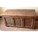 An early 18th century oak coffer, the triple plank top above carved front panels raised on stile